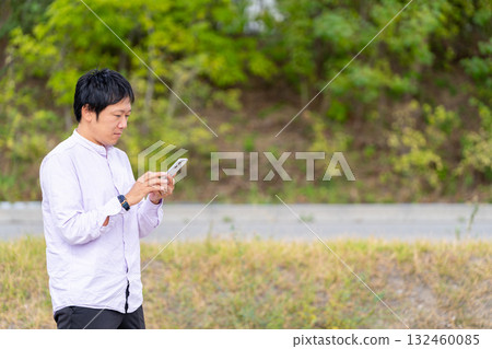 A business man operating a smartphone and checking notifications outdoors 132460085