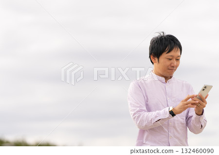 A business man operating a smartphone and checking notifications outdoors A business man operating a smartphone and checking notifications outdoors 132460090