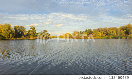 A deep river surrounded by trees and plants. Reed beds. Boats on the water. A deep river surrounded by trees and plants. Reed beds. Boats on the water. 132460489