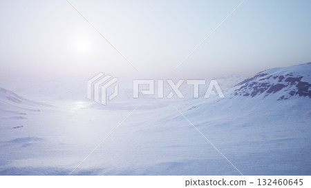 A vast, icy terrain stretches under the gentle glow of the early sun. Snow covered mountains rise in the distance, enveloped in a tranquil and ethereal atmosphere, signaling a new day. A vast, icy terrain stretches under the gentle glow of the early sun. Snow covered mountains rise in the distance, enveloped in a tranquil and ethereal atmosphere, signaling a new day. 132460645