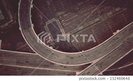 Empty streets create a surreal atmosphere as a winding road snakes through an urban landscape, showcasing the blend of modern architecture and shadows cast by streetlights at night. Empty streets create a surreal atmosphere as a winding road snakes through an urban landscape, showcasing the blend of modern architecture and shadows cast by streetlights at night. 132460648