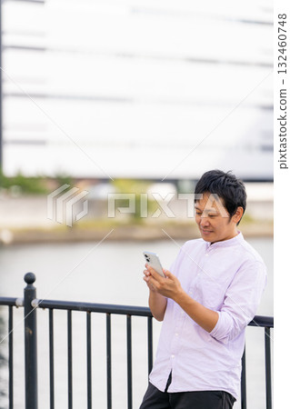 A man operating a smartphone with the sea in the background | Plenty of copy space A man operating a smartphone with the sea in the background | Plenty of copy space 132460748