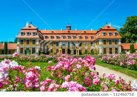 Panoramic view of Rajec Jestrebi Chateau on a sunny summer day with blue sky, blooming pink roses, and a fountain in front of the historical building. 132460758