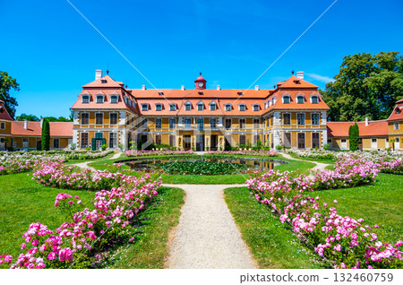 Panoramic view of Rajec Jestrebi Chateau on a sunny summer day with blue sky, blooming pink roses, and a fountain in front of the historical building. 132460759