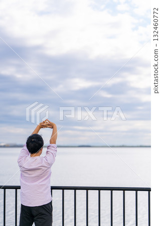 Man stretching with arms outstretched against the ocean background | Take a breather and refresh 132460772
