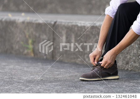 Man tying his shoelaces on the stairs Man tying his shoelaces on the stairs 132461048