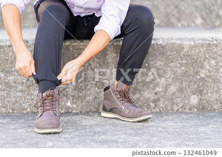 Man tying his shoelaces on the stairs Man tying his shoelaces on the stairs 132461049