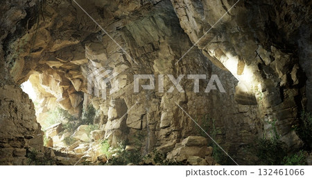 A stunning cave interior reveals textured stone walls and glowing light spots. Lush greenery peeks through openings, creating a serene natural atmosphere during daylight. 132461066