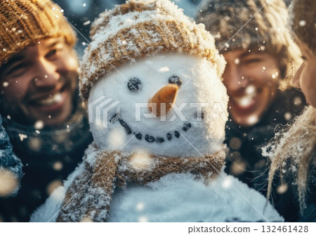 Group of adults in winter coats and scarves building a snowman. A playful and joyful winter scene outdoors. 132461428