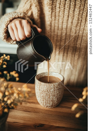 Hands holding a mug while hot coffee is being poured. The comfort of slow living captured in soft light. Hands holding a mug while hot coffee is being poured. The comfort of slow living captured in soft light. 132461447