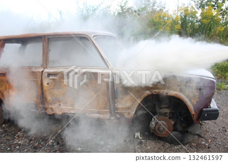 extinguishing the car with a fire extinguisher. The car is in white smoke extinguishing the car with a fire extinguisher. The car is in white smoke 132461597