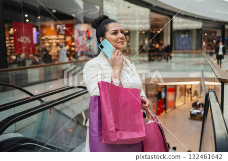 Woman shopping and chatting on the phone in a modern mall 132461642