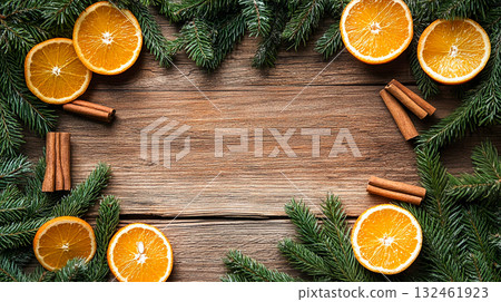A Christmas or New Year's composition decorated with fir branches, orange slices, and brown cinnamon sticks. These elements are arranged around the perimeter, leaving the center empty. 132461923