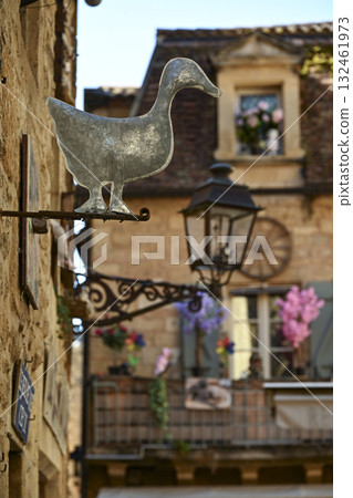 Charming streets of Sarlat-La-Caneda featuring a metal duck sign and beautifully decorated buildings 132461973