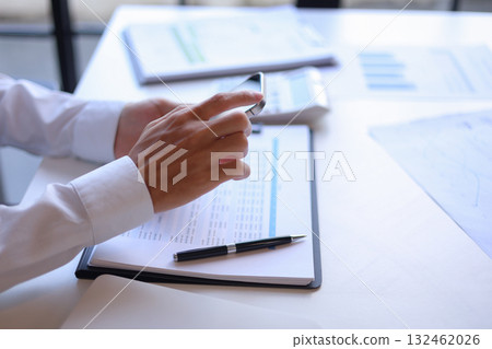 Businessman working in office using phone and laptop. Organize and manage projects efficiently using technology and planning, task management, monitoring, reporting, collaborating to archive goal. 132462026