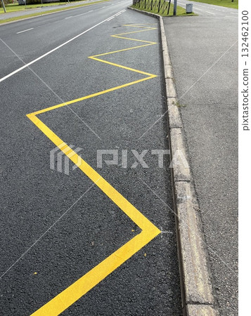 Yellow zigzag road markings on asphalt surface, creating a striking visual pattern along the roadside, enhancing traffic guidance and safety awareness for drivers Yellow zigzag road markings on asphalt surface, creating a striking visual pattern along the roadside, enhancing traffic guidance and safety awareness for drivers 132462100