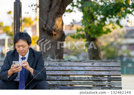 午休期間收集資訊 | 商人在公園看智慧型手機 132462149