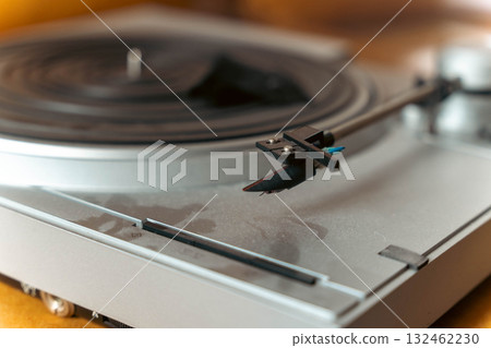 Close-up of a vintage turntable with a stylus arm positioned above a vinyl record, showcasing the intricate details of the audio equipment and its nostalgic charm Close-up of a vintage turntable with a stylus arm positioned above a vinyl record, showcasing the intricate details of the audio equipment and its nostalgic charm 132462230