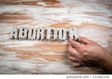 Word abortion formed with solid concrete letters on a wooden surface. Symbolizing law, health 132462240