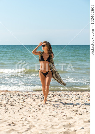 Woman looking over ocean horizon, Caucasian female explorer scanning expansive sea horizon with breezy sarong Woman looking over ocean horizon, Caucasian female explorer scanning expansive sea horizon with breezy sarong 132462605