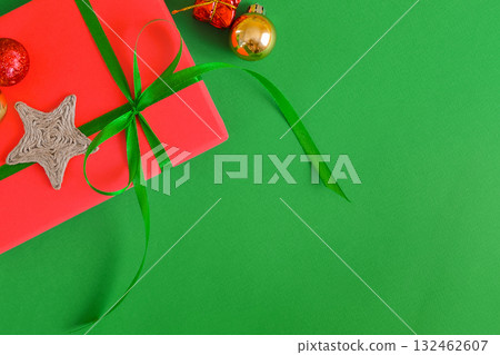 Green Christmas background with space for text, a gift, and Christmas tree decorations. Top view. Green Christmas background with space for text, a gift, and Christmas tree decorations. Top view. 132462607