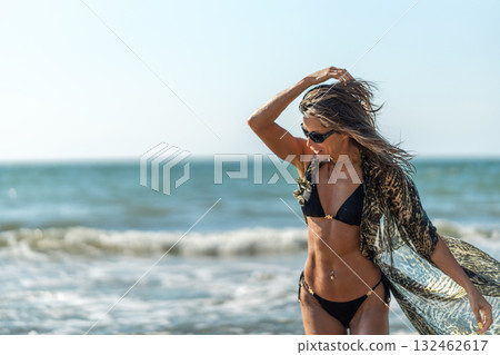 Beachside thoughtful portrait, Serene woman with flowing shawl, Contemplative woman stands at seaside with graceful 132462617