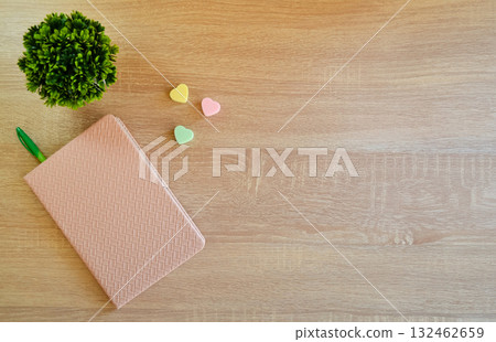 On the wooden surface of the table there is a notebook with a pen and elastic bands 132462659