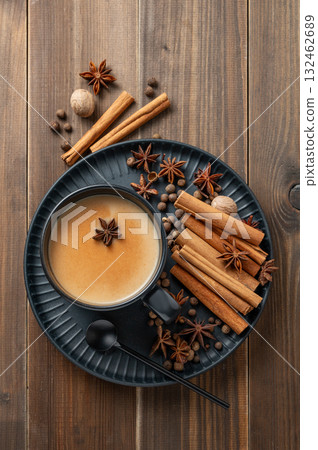 Traditional Indian masala chai tea with milk and spices in a black cup on a wooden background Traditional Indian masala chai tea with milk and spices in a black cup on a wooden background 132462689