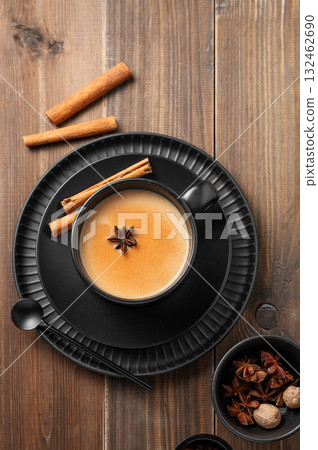 Traditional Indian masala chai tea with milk and spices in a black cup on a dark wooden background Traditional Indian masala chai tea with milk and spices in a black cup on a dark wooden background 132462690