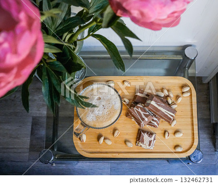 Top view of a coffee cup with chocolate and a flower in a vase on a table. 132462731