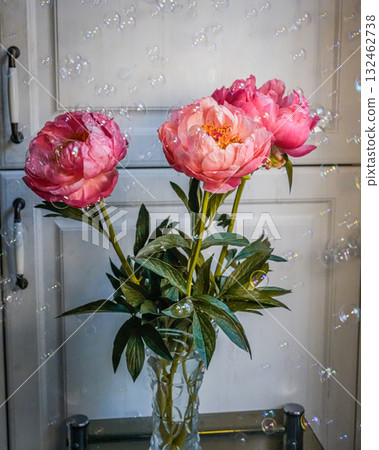 Medium shot of pink peonies in a glass vase with soap bubbles floating around. Medium shot of pink peonies in a glass vase with soap bubbles floating around. 132462738