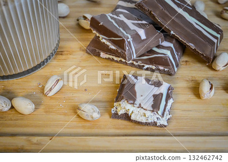 Warm close-up shot of a coffee cup beside chocolate pieces and nuts on a table. Perfect for cozy lifestyle, dessert, coffee break, and food photography concepts. Warm close-up shot of a coffee cup beside chocolate pieces and nuts on a table. Perfect for cozy lifestyle, dessert, coffee break, and food photography concepts. 132462742