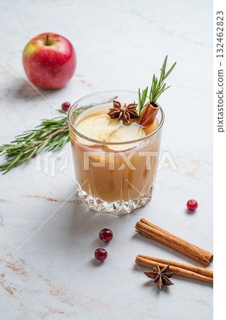 Hot apple cider with cinnamon, anise, and rosemary in glass on a marble background with cranberry Hot apple cider with cinnamon, anise, and rosemary in glass on a marble background with cranberry 132462823