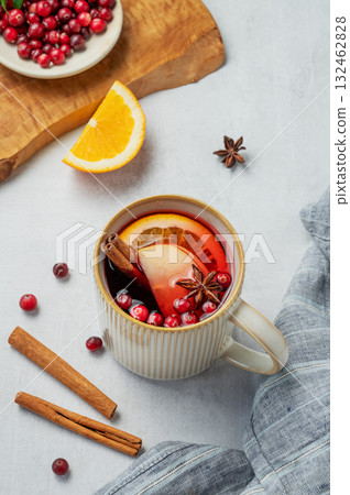 A hot cranberry Christmas drink in a mug on a wooden board on a light background with cinnamon 132462828