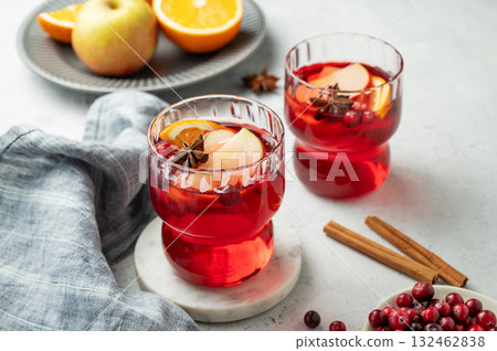 A cranberry drink in a two glasses on a light background with cinnamon, berries and napkin close up. A cranberry drink in a two glasses on a light background with cinnamon, berries and napkin close up. 132462838