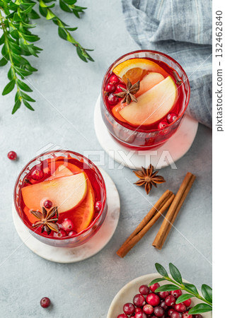 A cranberry drink in a two glasses on a light background with cinnamon, berries and green branch. 132462840