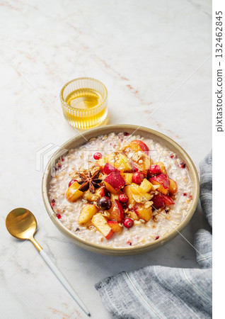 Overnight oatmeal with apple, cranberry and cinnamon in a plate on a marble background with honey Overnight oatmeal with apple, cranberry and cinnamon in a plate on a marble background with honey 132462845