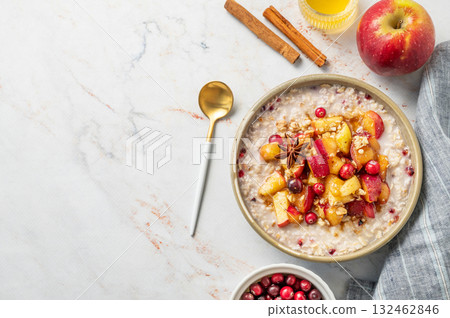 Flat lay of overnight oatmeal with apple, cranberry and cinnamon in a plate on a marble background Flat lay of overnight oatmeal with apple, cranberry and cinnamon in a plate on a marble background 132462846