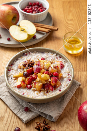 Overnight oatmeal with apple, cranberry and cinnamon in a plate on a wooden background with honey 132462848
