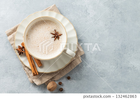 Traditional Indian masala chai tea with milk and spices in a white cup on a light blue background. Traditional Indian masala chai tea with milk and spices in a white cup on a light blue background. 132462863