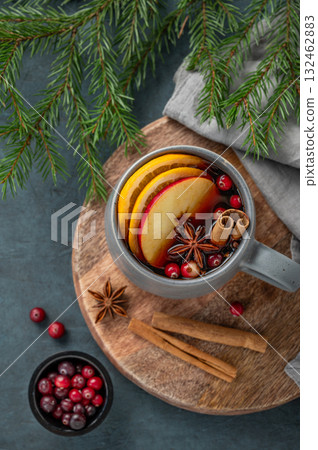A cup of red mulled wine with spices, orange, apple slices and cranberry on a dark background A cup of red mulled wine with spices, orange, apple slices and cranberry on a dark background 132462883