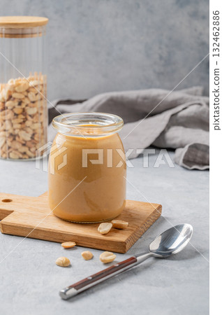 Creamy peanut butter in a jar on a wooden board on a blue background Creamy peanut butter in a jar on a wooden board on a blue background 132462886