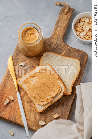 Peanut butter toast on a wooden board on a light background with nuts, knife and a napkin. 132462891