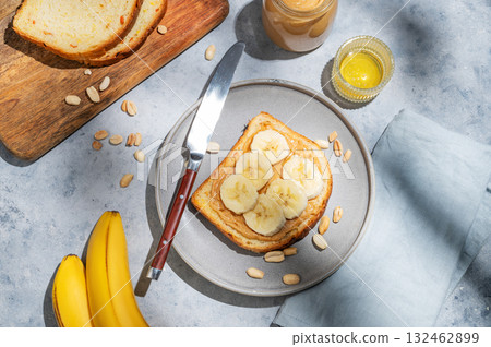 Peanut butter toast with banana on a plate on a blue background with spread, bread, fruit, honey  132462899