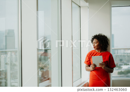 Businesswoman with tablet in hands standing by the window. London view panorama. Businesswoman with tablet in hands standing by the window. London view panorama. 132463060