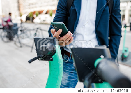 Businessman unlocking electric scooter with smartphone. 132463066