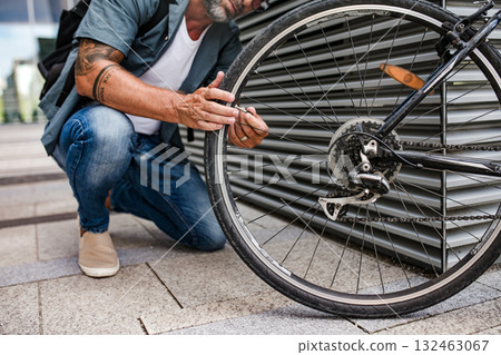 Man fixing bicycle wheel outdoors. 132463067