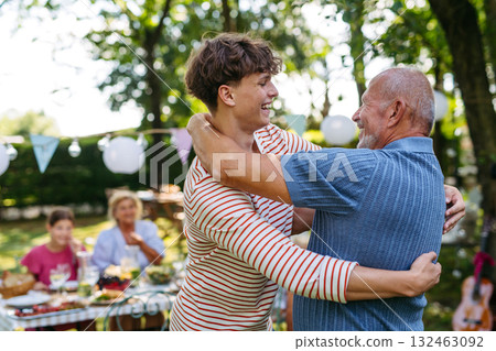 Grandson hugging his grandfather to greet him. 132463092