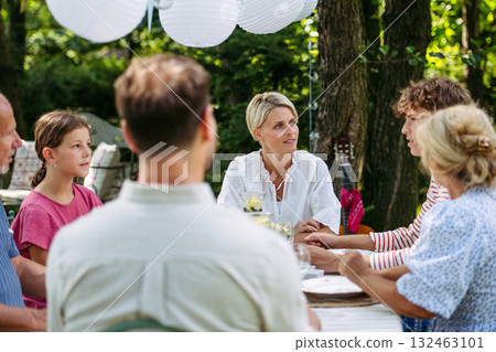 Family sharing food during garden grill party. 132463101