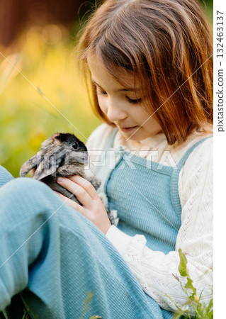 Young girl gently cuddles a fluffy bunny in her arms. 132463137